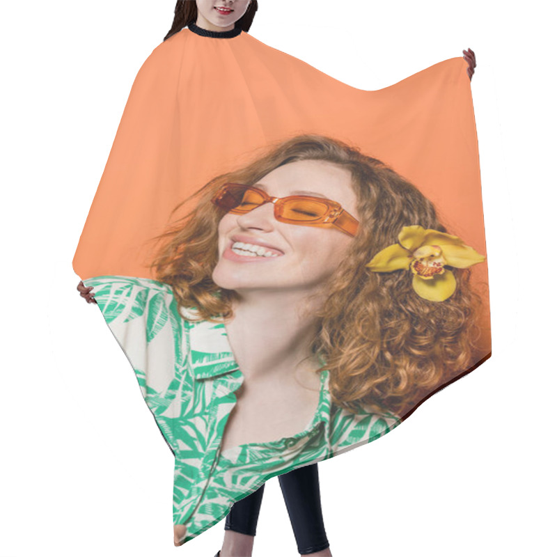 Personality  Positive Young Woman With Orchid Flower In Red Hair Wearing Sunglasses And Stylish Blouse While Standing On Orange Background, Summer Casual And Fashion Concept, Youth Culture Hair Cutting Cape