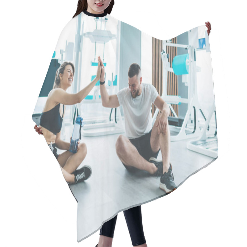 Personality  Full Body Of Laughing Fit Couple Giving Five While Sitting On Floor And Having Break During Workout In Modern Gym Hair Cutting Cape