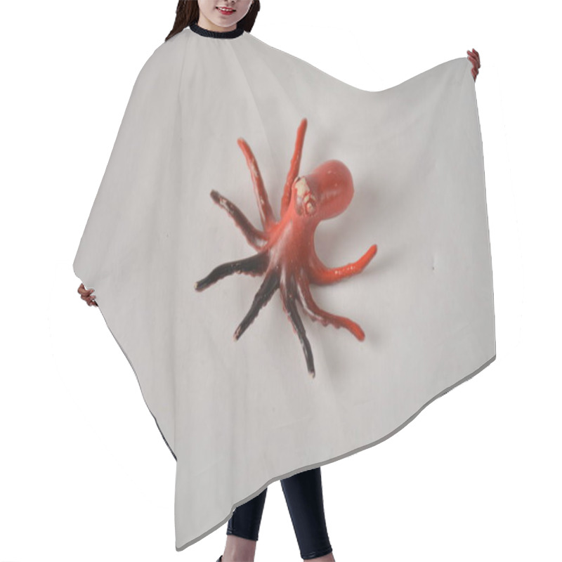 Personality  Small, Realistic Toy Octopus With Red And Black Tentacles On A White Background. Hair Cutting Cape