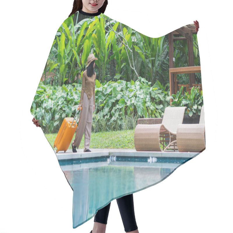 Personality  A Woman Walking By A Poolside With An Orange Suitcase, Wearing A Hat And Stylish Outfit. The Background Features Lush Greenery And A Wooden Structure, Creating A Tropical Vacation Vibe. Hair Cutting Cape