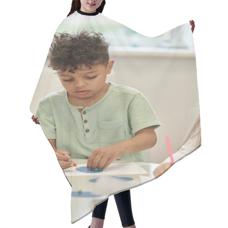 Personality  African American Child Paining With Pencil Near Friend And Blurred Teacher In Montessori Class Hair Cutting Cape