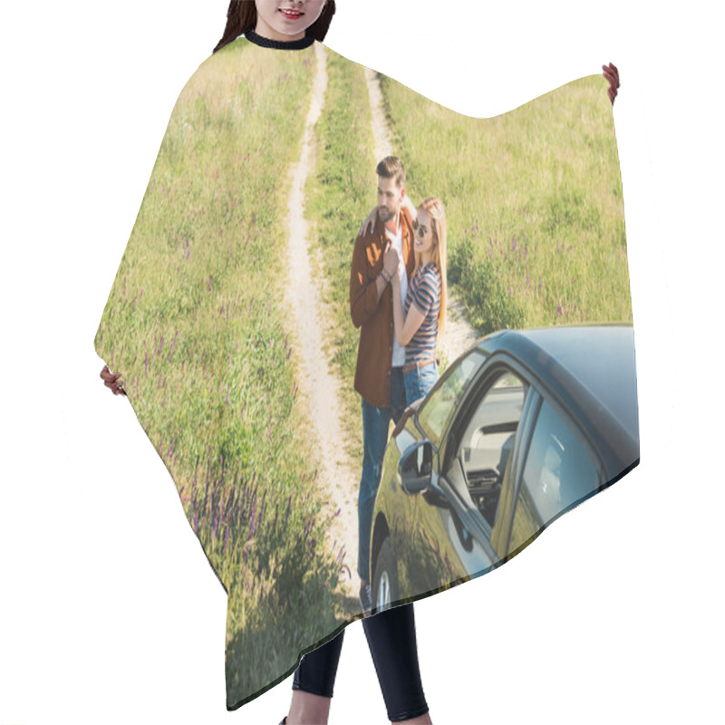 Personality  Elevated View Of Young Stylish Couple Embracing Near Car In Rural Field  Hair Cutting Cape