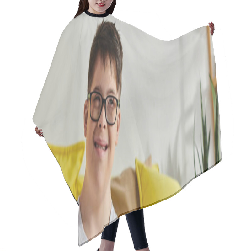 Personality  A Adorable Boy With Down Syndrome With Glasses Sits Calmly On A Couch In A Cozy Room. Hair Cutting Cape