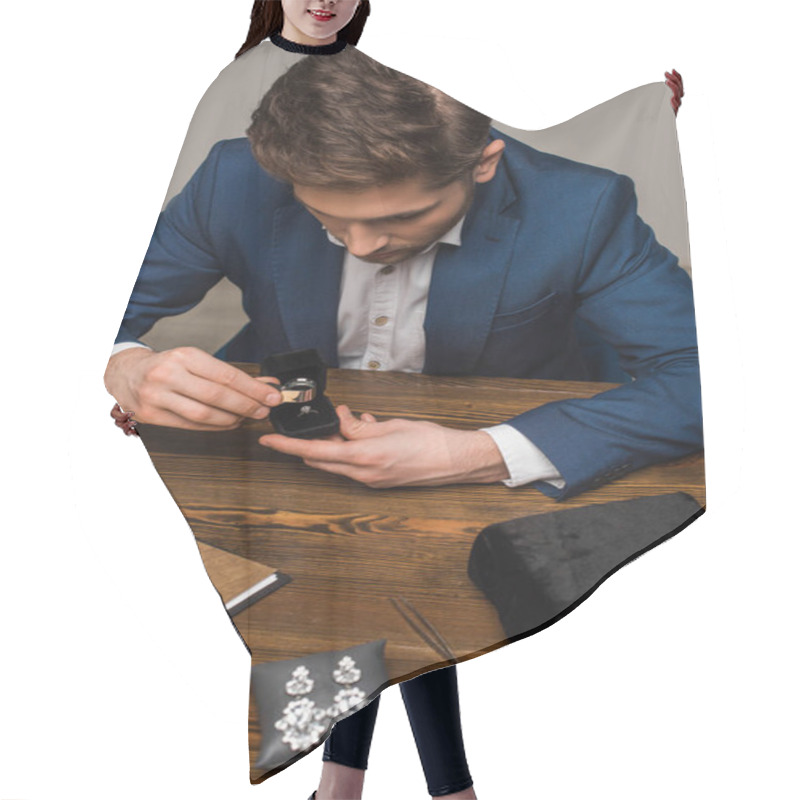 Personality  Jewelry Appraiser Examining Jewelry Ring With Magnifying Glass Near Jewelry On Table In Workshop Hair Cutting Cape