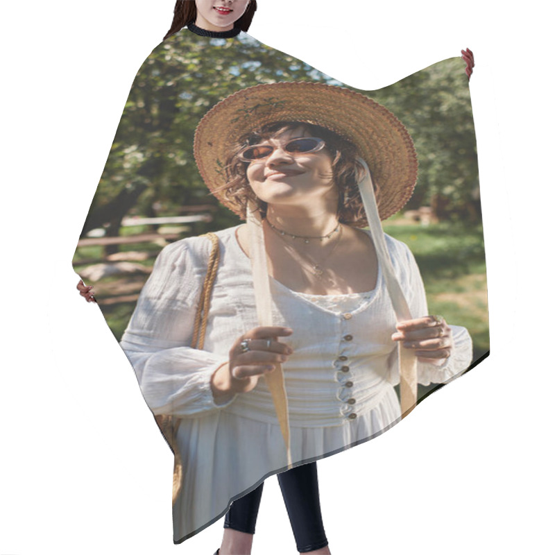 Personality  A Young Woman With Dark Hair Wears A White Blouse And A Straw Hat, Smiling As She Enjoys The Summer Sunshine In A Garden Setting. Hair Cutting Cape