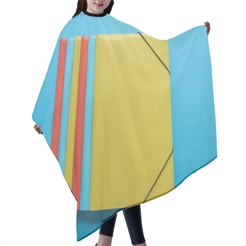 Personality  Top View Of Red, Blue And Yellow Paper Binders On Blue Hair Cutting Cape