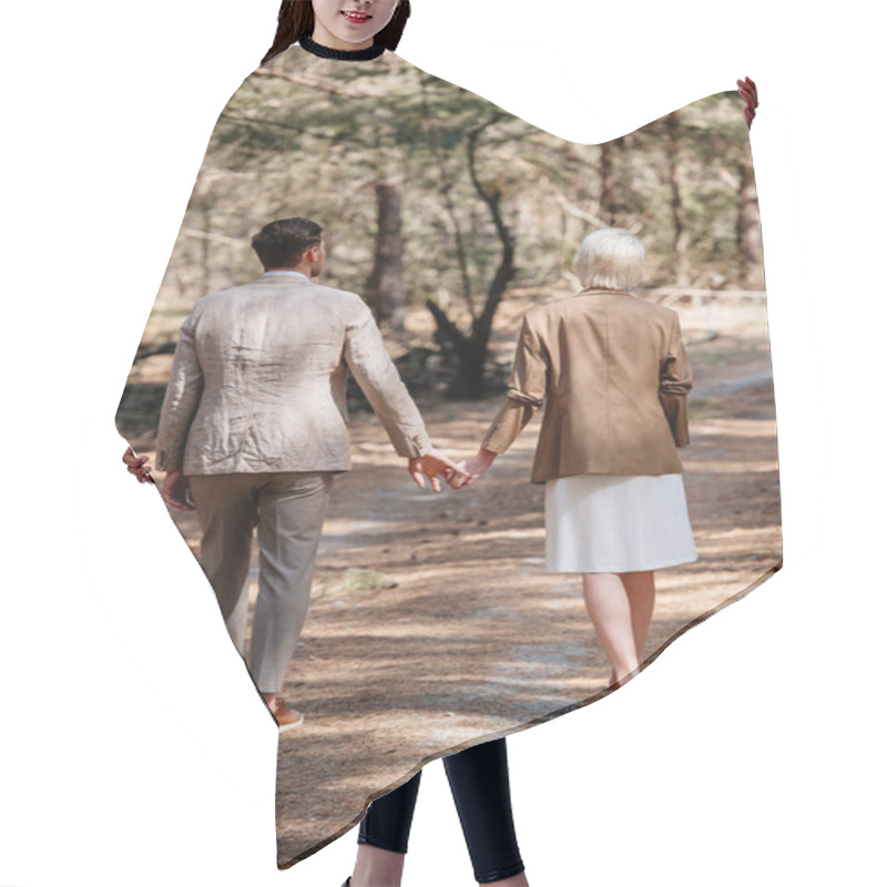 Personality  Back View Of Stylish Couple Holding Hands And Walking In Forest Hair Cutting Cape