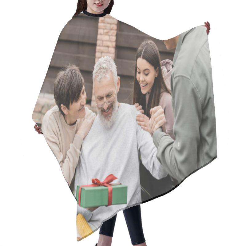 Personality  Smiling Middle Aged Man Holding Gift Box Near Children And Wife During Barbeque Party With Summer Food And Parents Day Celebration At Backyard In June, Celebrating Parenthood Day Concept Hair Cutting Cape