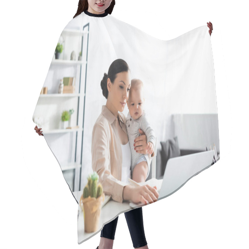 Personality  Selective Focus Of Attractive Mother Holding In Arms Baby Boy And Working From Home Hair Cutting Cape