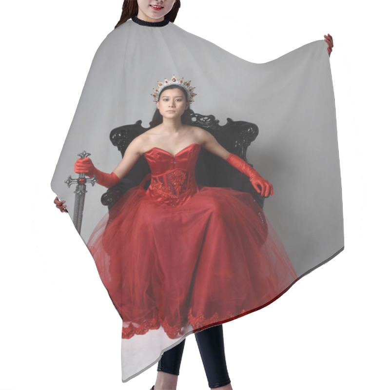 Personality  Full Length  Portrait Of Beautiful Young Asian Woman Wearing Red Corset, Long Opera Gloves And Ornate Gothic Queen Crown. Graceful Posing While Seated On Chair, Isolated On Studio Background. Hair Cutting Cape