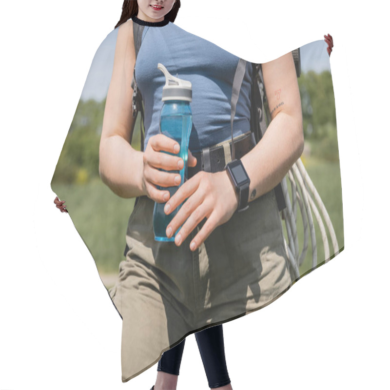 Personality  Cropped View Of Young Tattooed Female Hiker With Smartwatch And Backpack Holding Sports Bottle While Standing With Blurred Landscape At Background, Solo Hiking Journey Concept, Summer Hair Cutting Cape