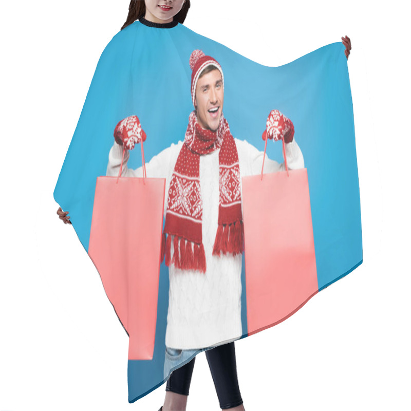 Personality  Happy Young Adult Man In Mittens Holding Red Paper Bags Isolated On Blue Hair Cutting Cape