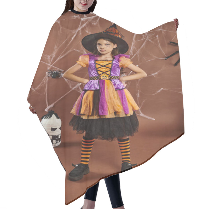 Personality  Serious Girl In Halloween Costume And Witch Hat Standing With Hands On Hips On Brown Backdrop Hair Cutting Cape