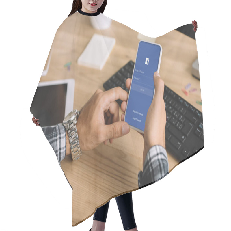 Personality  Cropped Shot Of Man Using Smartphone With Facebook App On Screen At Workplace Hair Cutting Cape