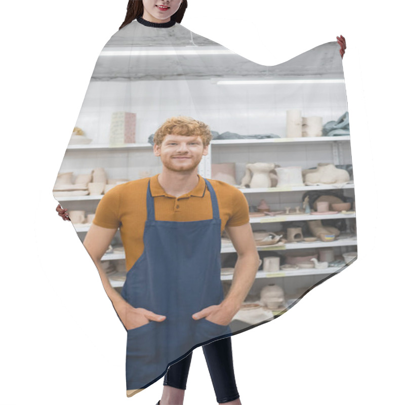 Personality  Smiling Redhead Artisan In Apron Looking At Camera In Pottery Studio  Hair Cutting Cape