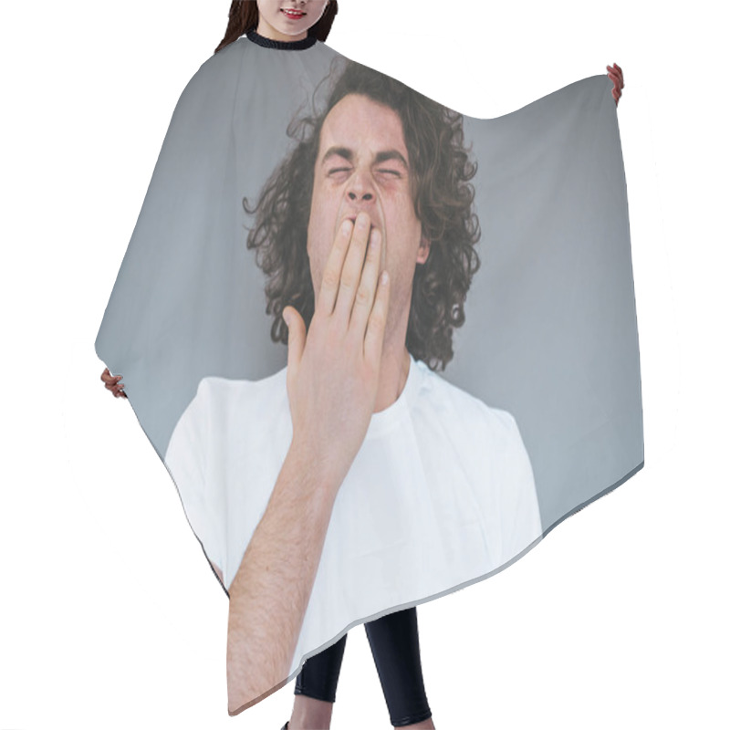 Personality  Portrait Of Tired Or Bored Caucasian Young Male Model With Curly Hair Covering Mouth While Yawning, Feeling Exhausted After Overwork. Student Stylish Man Having Sleepy Look After Lessons. Hair Cutting Cape