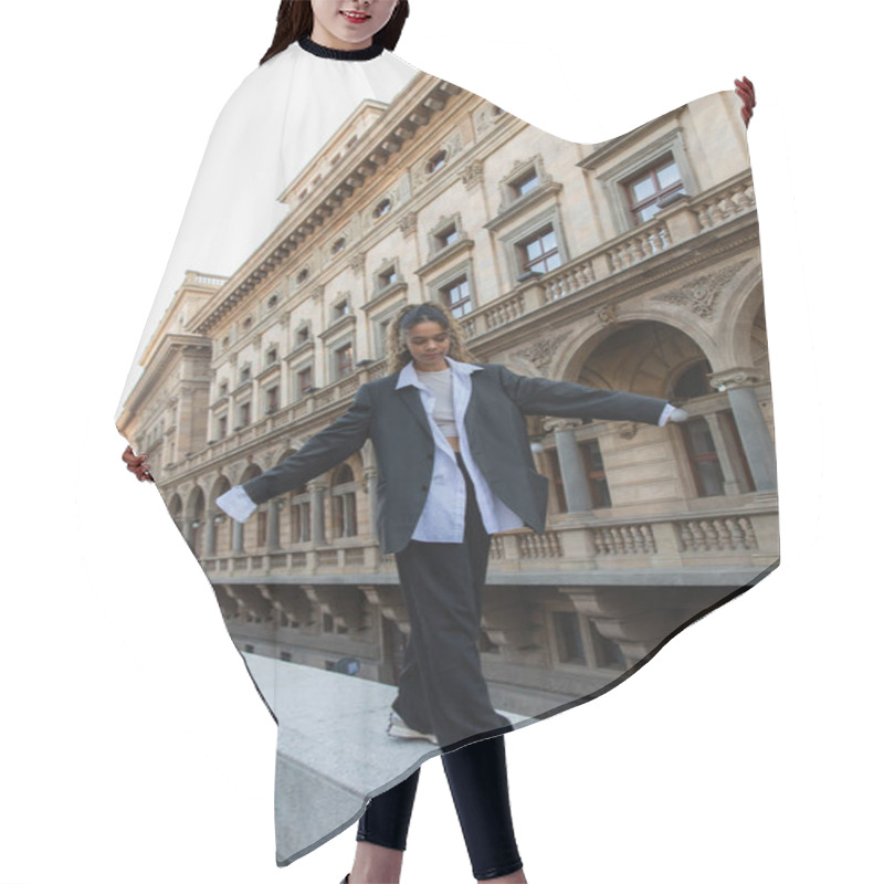 Personality  Full Length Of Curly African American Woman In Oversize Suit Walking With Outstretched Hands Near Building Of National Theater In Prague Hair Cutting Cape