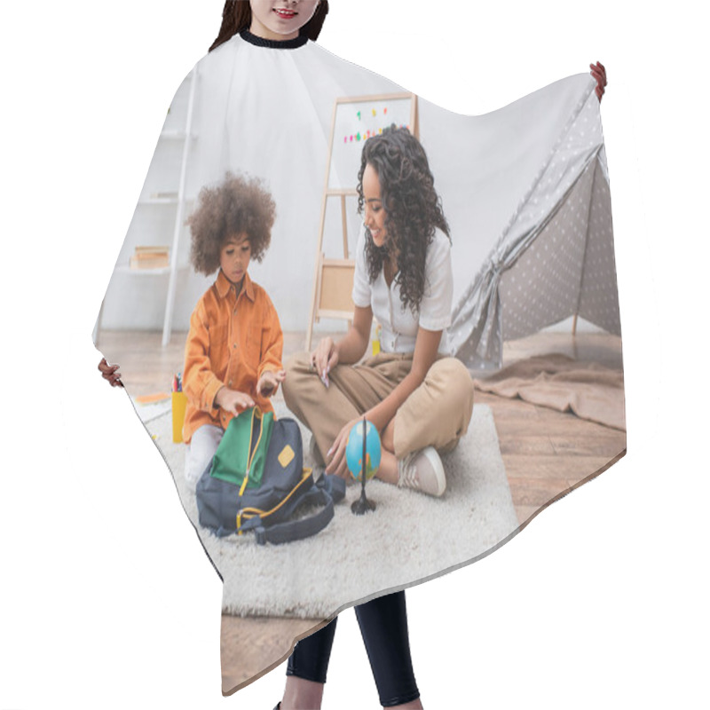 Personality  Toddler Kid Sitting Near Globe, Notebooks And African American Mom In Living Room  Hair Cutting Cape