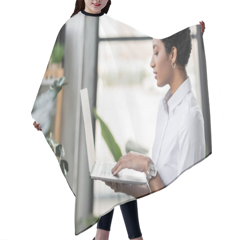 Personality  Side View Of Young African American Businesswoman Standing In Office And Using Laptop With Blank Screen Hair Cutting Cape