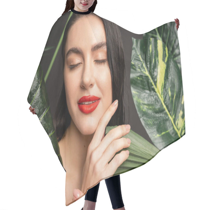 Personality  Charming Young Woman With Brunette Hair And Red Lips Posing With Closed Eyes Around Tropical And Exotic Green Palm Leaves With Raindrops On Them Isolated On Grey Background  Hair Cutting Cape