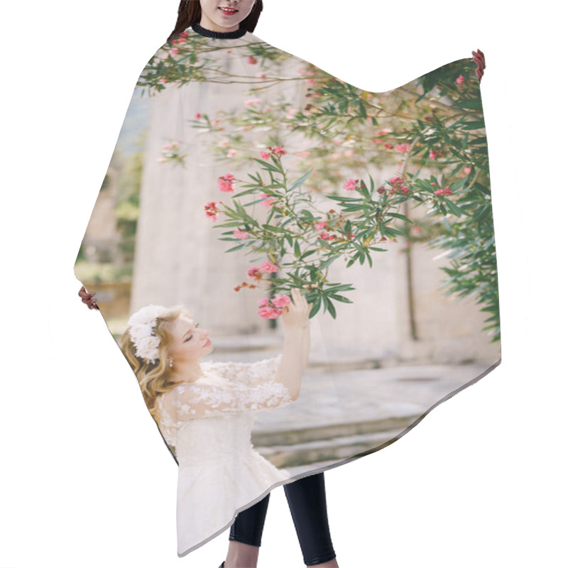 Personality  The In Wreath Bride Stands Under A Blooming Oleander Near The Old Church And Touching It  Hair Cutting Cape