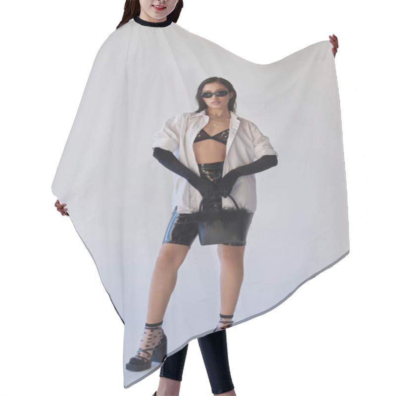 Personality  Trendy Look, Fashion Statement, Brunette Asian Woman In Sunglasses Posing With Feathered Purse On Grey Background, Model In Latex Shorts, Black Gloves And White Shirt, Youth, Full Length  Hair Cutting Cape