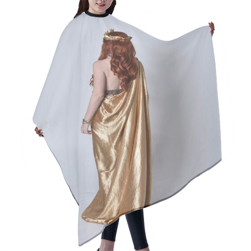 Personality  Full Length Portrait Of Girl With Red Hair Wearing Long Grecian Toga And Golden Wreath. Standing Pose With Back To The Camera,  Isolated Against A Grey Studio Background. Hair Cutting Cape