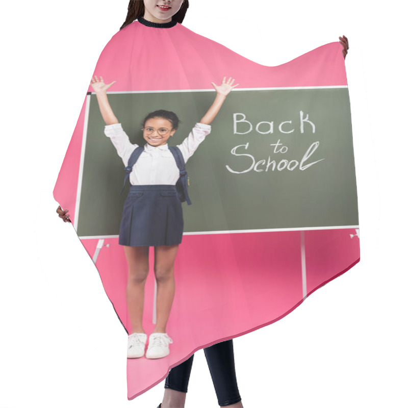 Personality  Happy African American Schoolgirl In Glasses With Hands In Air Near Back To School Inscription On Green Chalkboard On Pink Background Hair Cutting Cape