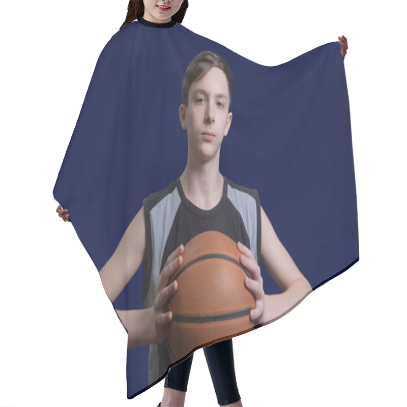 Personality  Portrait Of A Teen Basketball Player. The Guy In The Black T-shirt Holds The Ball In His Hands. The Concept Of A Sports Poster Or Design News About Basketball Competitions. Isolated On Blue Background. Hair Cutting Cape