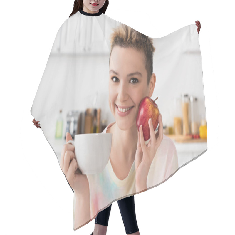 Personality  Happy Pangender Person With Cup Of Tea And Fresh Apple Looking At Camera In Kitchen Hair Cutting Cape