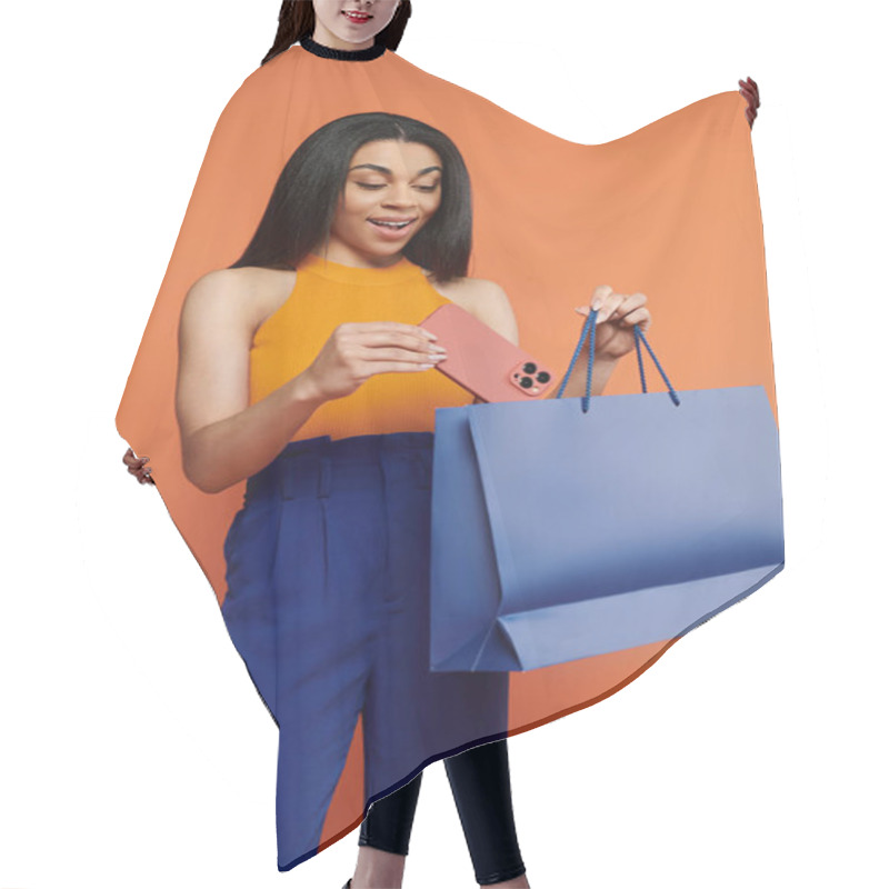 Personality  A Delighted Young Woman Admires Her New Phone While Holding Shopping Bags. Hair Cutting Cape