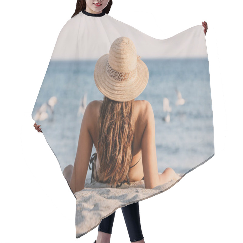 Personality  Young Girl In A Bathing Suit And Hat Sitting On The Sand On The Beach, Looking To The Seagulls In The Sea. Beautiful Lady Is Facing The Ocean With Her Back To The Lens Hair Cutting Cape