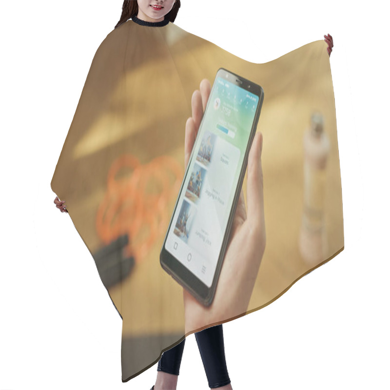 Personality  Close-up POV: Fit Woman Holds Smartphone, Uses Fitness Tracking App With Premium Workout Videos, Chooses Desired Exercise Clip. Mock-up Training Application Software Hair Cutting Cape