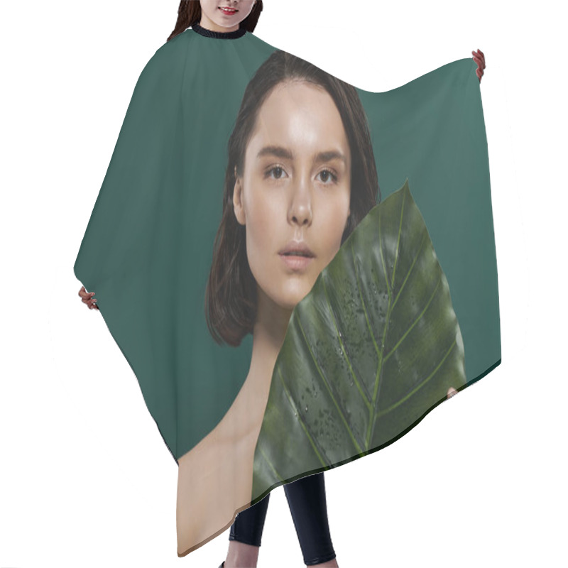 Personality  A Woman Poses Against A Green Background, Holding A Large Green Leaf. Hair Cutting Cape