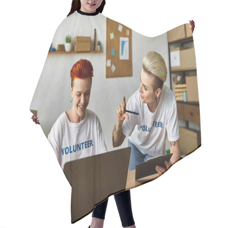 Personality  Two Women In Volunteer T-shirts Working Together On A Laptop At A Table. Hair Cutting Cape