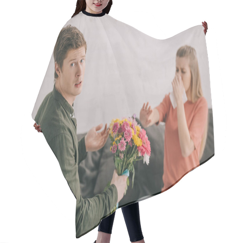 Personality  Upset Man Holding Flowers And Looking At Camera Near Blonde Woman With Pollen Allergy Sneezing In Tissue  Hair Cutting Cape