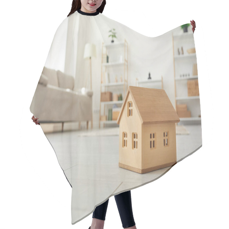 Personality  Close Up Of Small Model Of Wooden One-story House On Floor In Living Room Of Bright Apartment. Concept Of Buying Property, Real Estate, Renting And Home Insurance. Selective Focus. Hair Cutting Cape