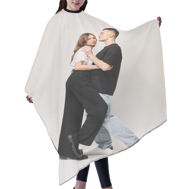 Personality  A Young Couple In Love Dances Together With Passion In A Studio, Against A Grey Background. Hair Cutting Cape