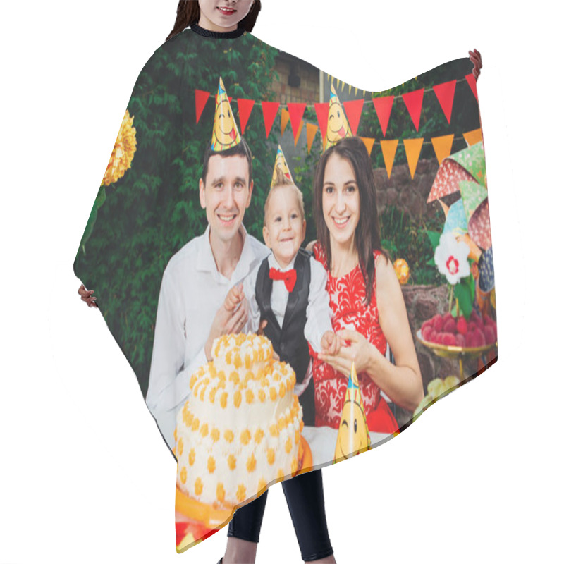 Personality  Children Birthday Theme. Family Of Three Caucasian People Sitting In Backyard Of The House At A Festive Decorated Table In Funny Hats And Caps On Their Heads. Joy And Happiness Cake And Pastry Snack Hair Cutting Cape