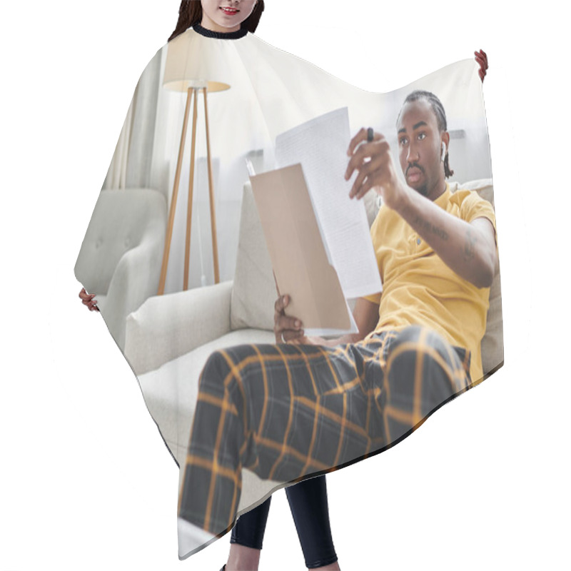 Personality  A Young African American Man Engaged In Remote Work, Examining Important Documents In Comfort. Hair Cutting Cape