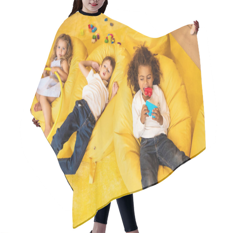 Personality  High Angle View Of Multiethnic Kids Lying On Bean Bag Chairs With Toys In Kindergarten Hair Cutting Cape