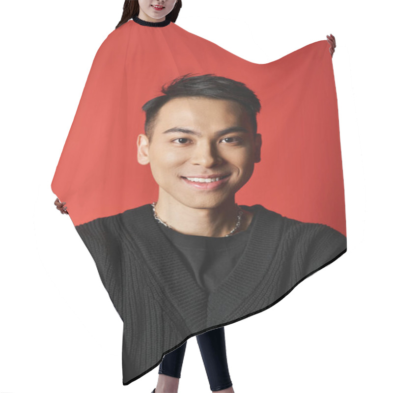 Personality  A Handsome Asian Man Is Smiling Warmly At The Camera, Wearing A Chic Black Sweater On A Vibrant Red Studio Backdrop. Hair Cutting Cape