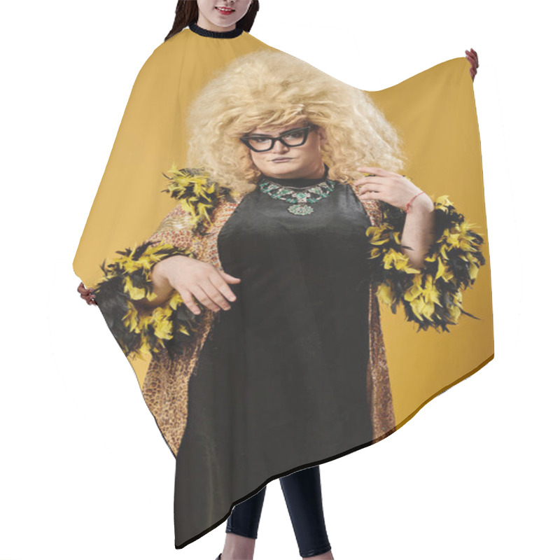 Personality  A Queer Person In A Black Dress With A Yellow And Black Feather Boa Stands Against A Yellow Background. Hair Cutting Cape