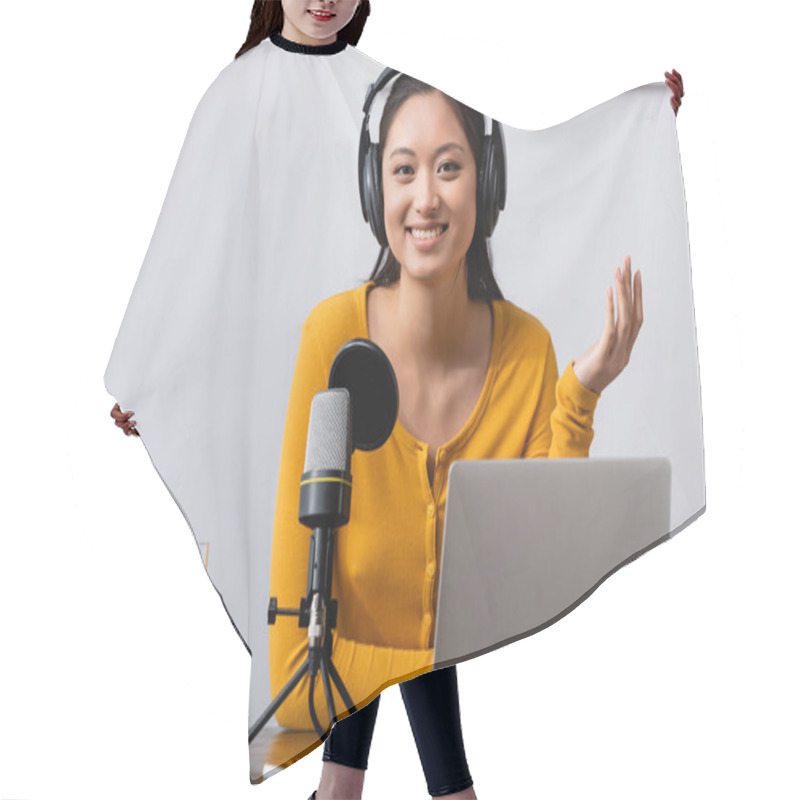 Personality  Excited Asian Radio Host In Wireless Headphones Looking At Camera While Sitting Near Microphone And Laptop Hair Cutting Cape