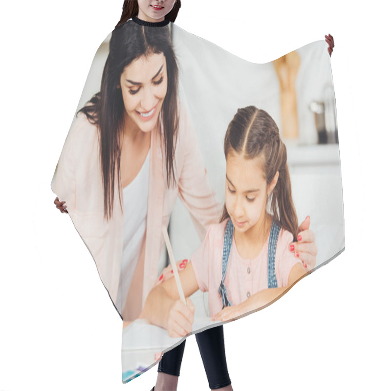 Personality  Happy Mother Looking At Cute Daughter Drawing On Paper At Home  Hair Cutting Cape