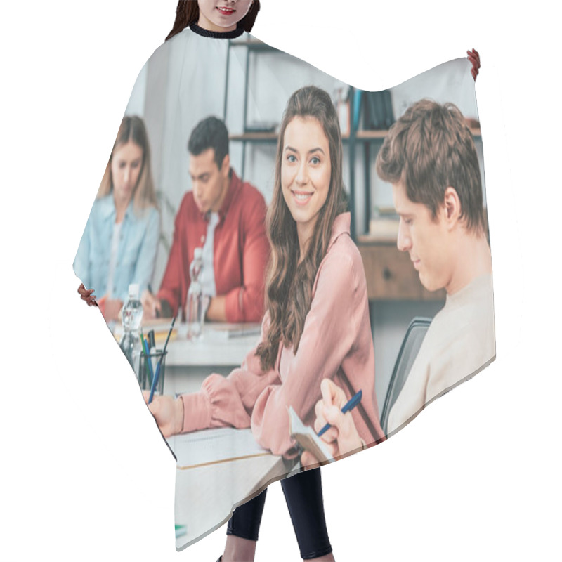 Personality  Charming Student Writing In Notebook And Looking At Camera With Smile Hair Cutting Cape