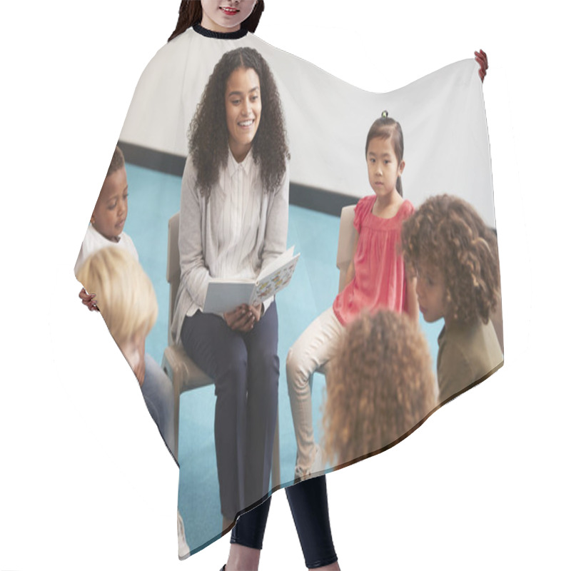 Personality  Young Female School Teacher Reading A Book To Kindergarten Children, Sitting On Chairs In A Circle In The Classroom Listening, Close Up Hair Cutting Cape