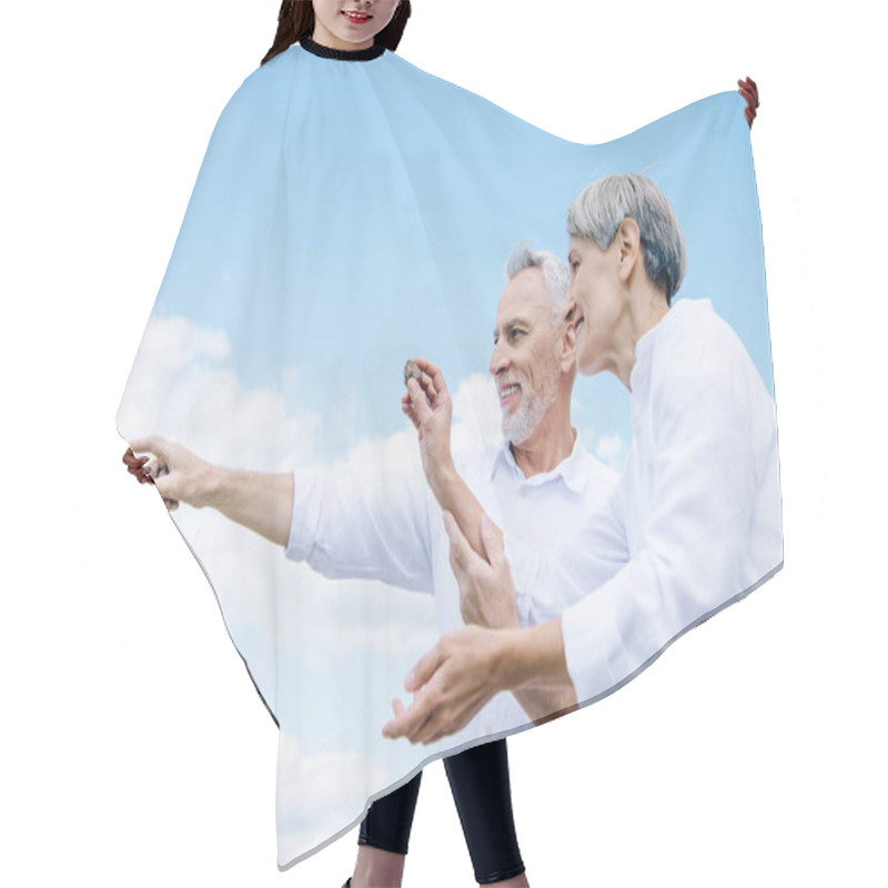 Personality  Happy Smiling Senior Couple Holding Stone And Pointing With Finger Under Blue Sky Hair Cutting Cape