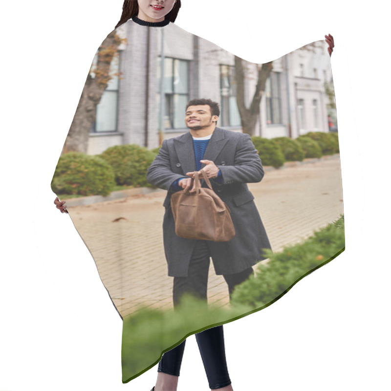 Personality  A Confident Man Walks Casually Down A Tree Lined Street Holding A Leather Bag While Smiling. Hair Cutting Cape