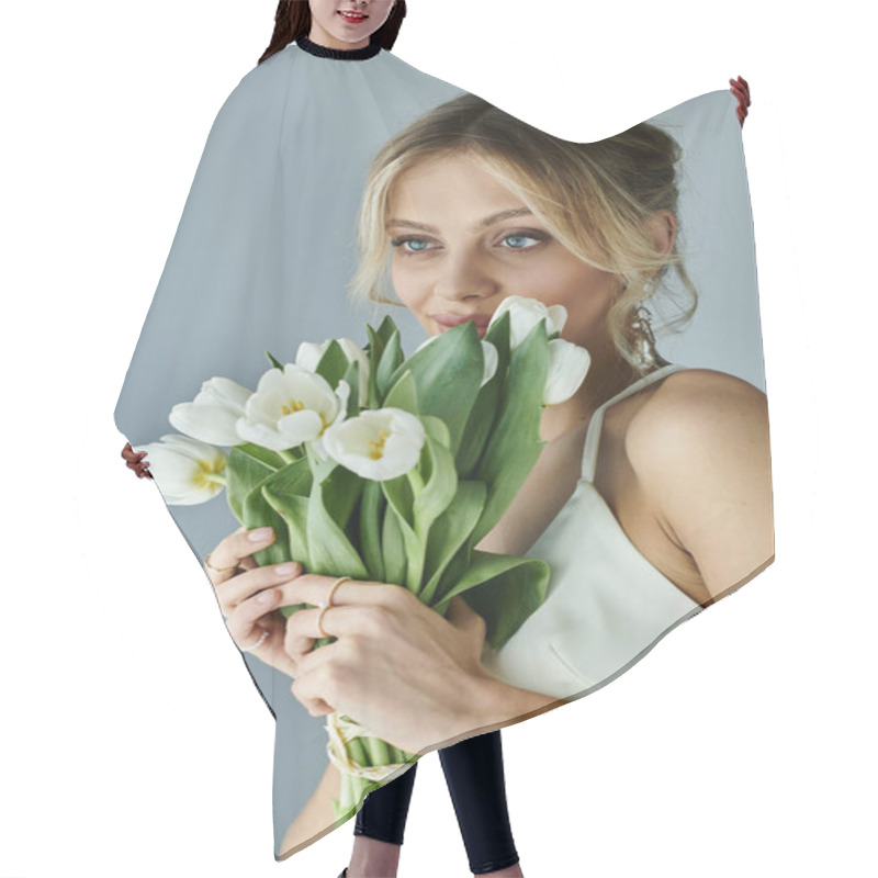 Personality  A Beautiful Young Blonde Woman Gracefully Holds A Bouquet Of White Flowers Against A Soft Grey Background. Hair Cutting Cape